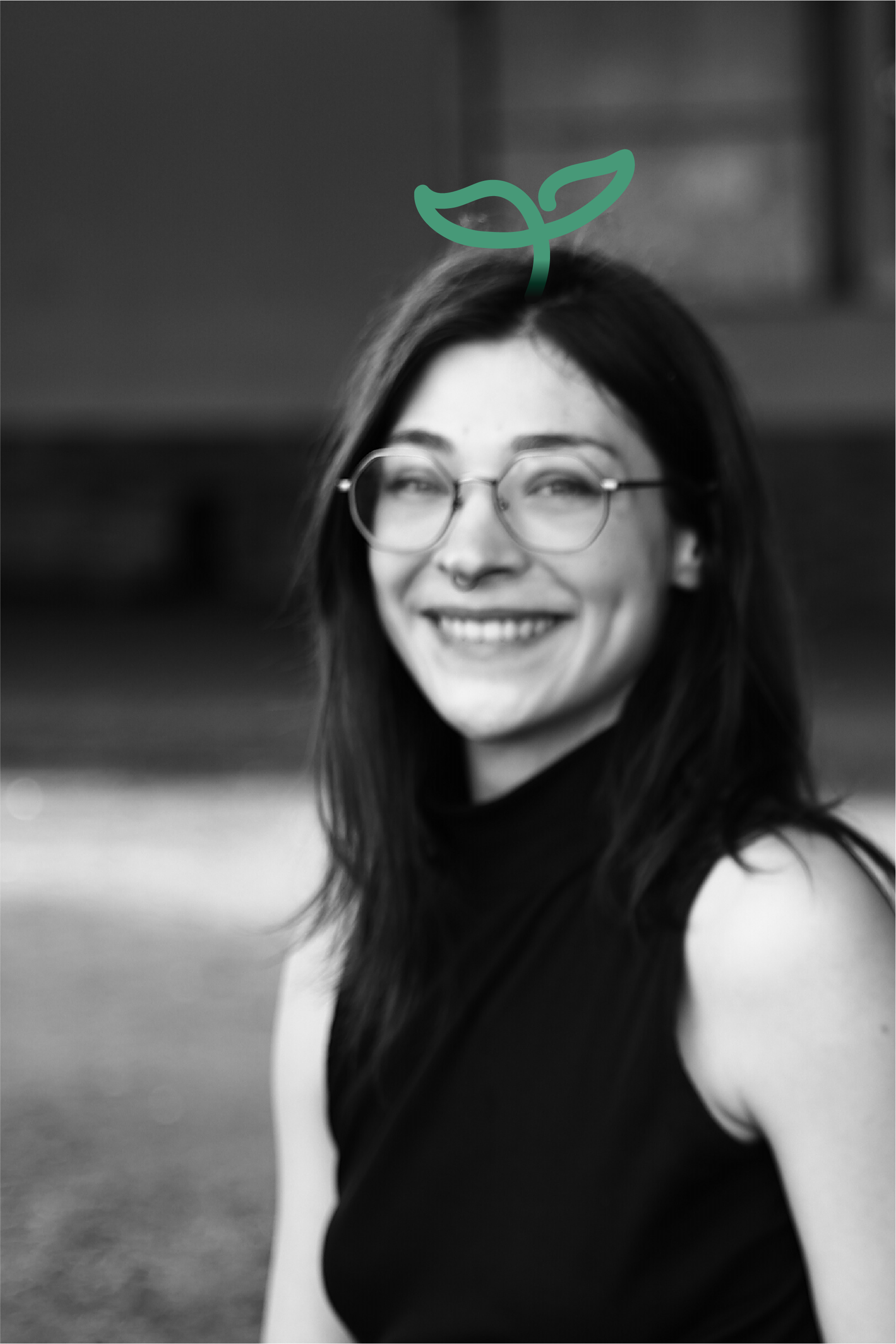 black and white image of a young person with glasses smiling into the camera. A line drawing of a small plant placed on the head.
